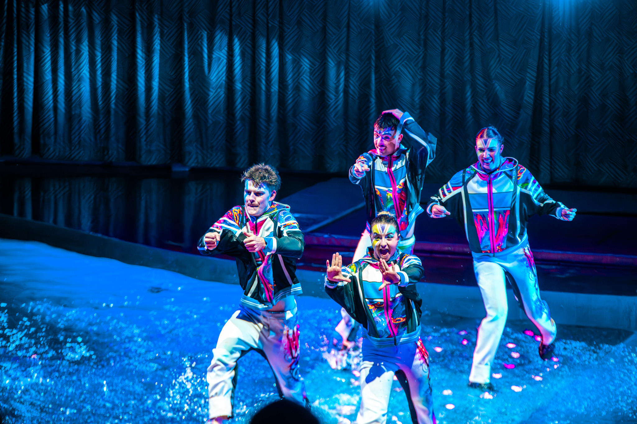 Dancers moving through shallow water on stage
