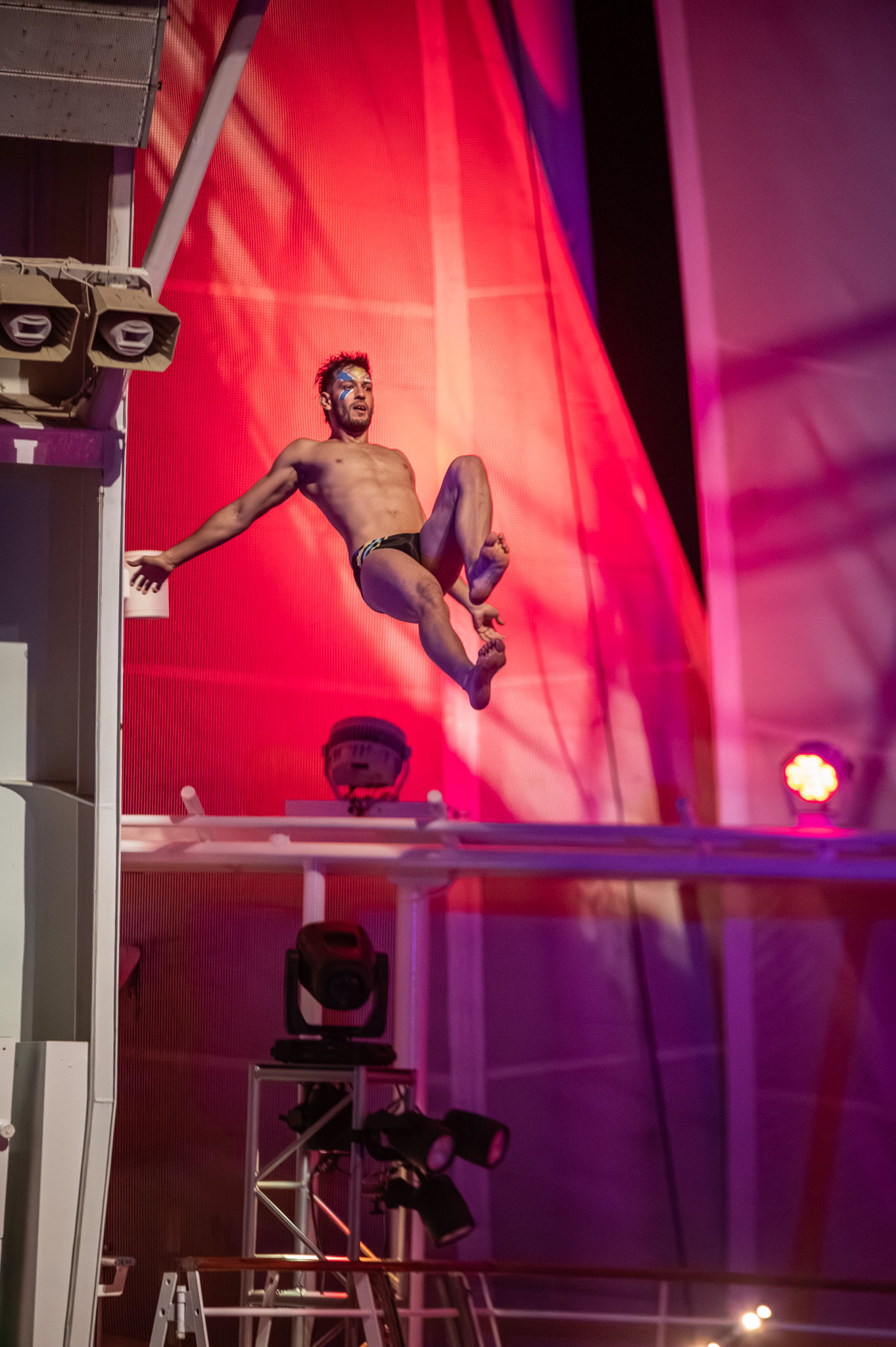 Live performer leaping with a bright red stage backdrop
