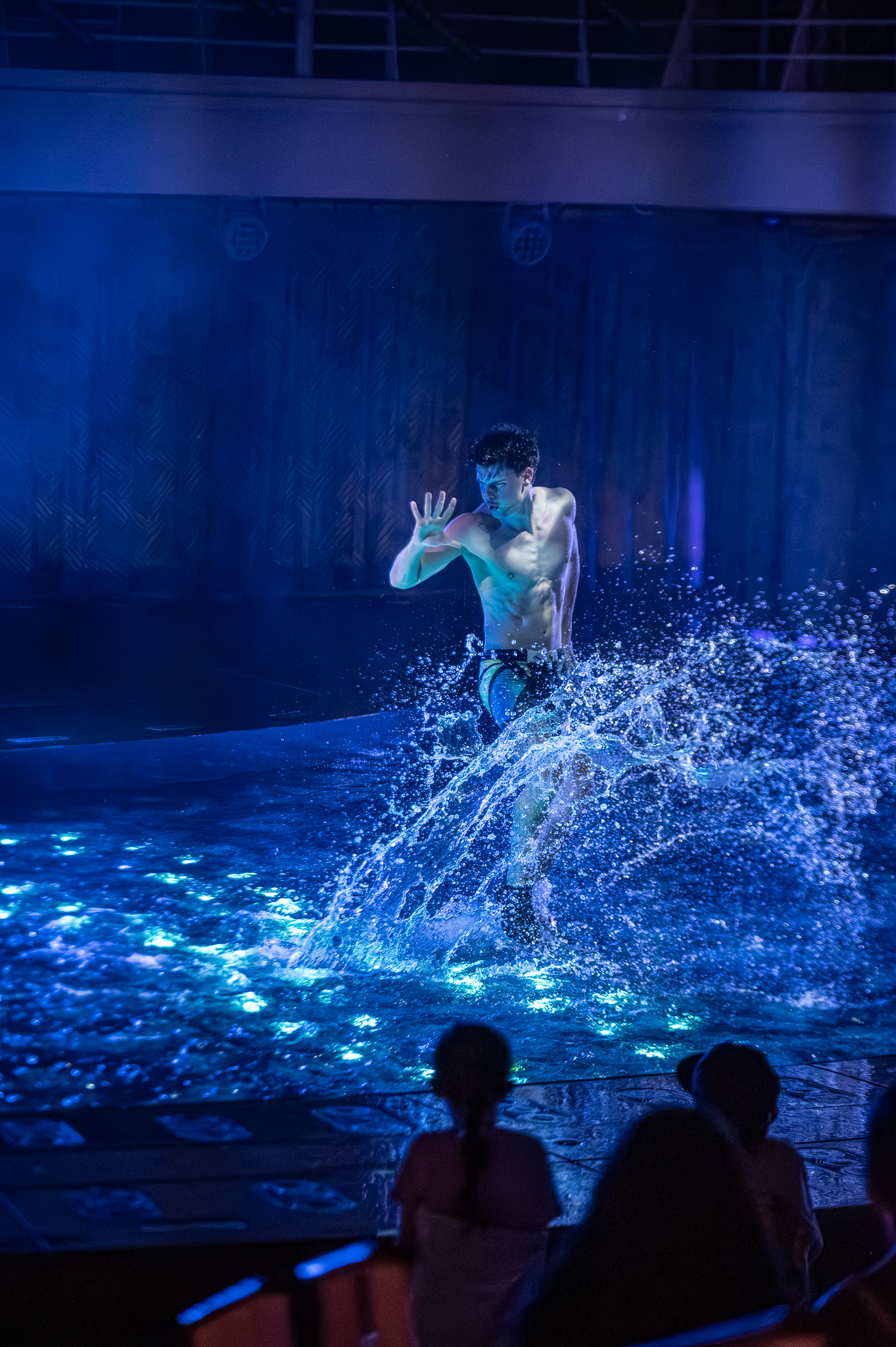 Performer and dancers in a brightly lit water show