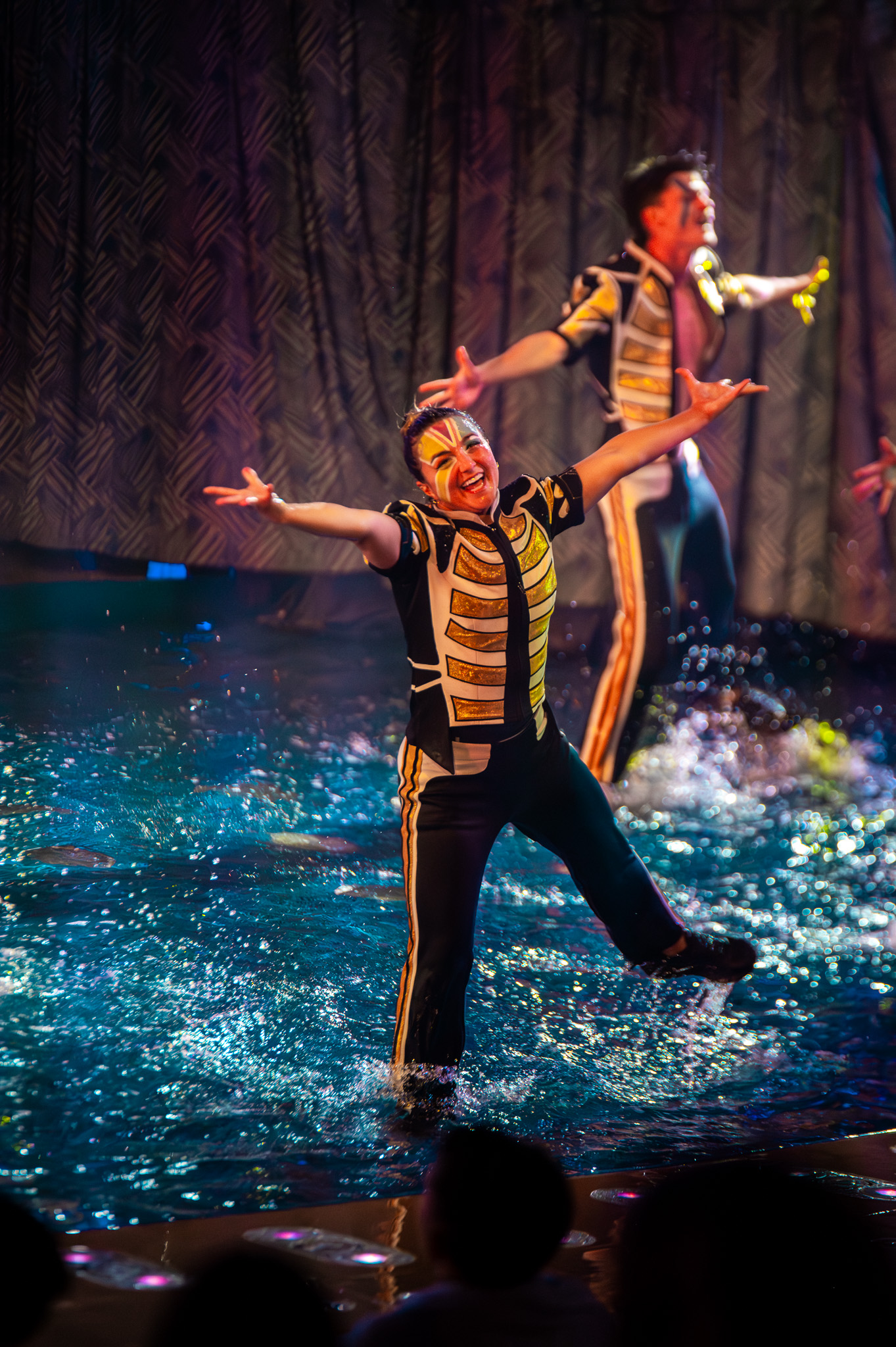 Performer flying across the stage framed by water arcs