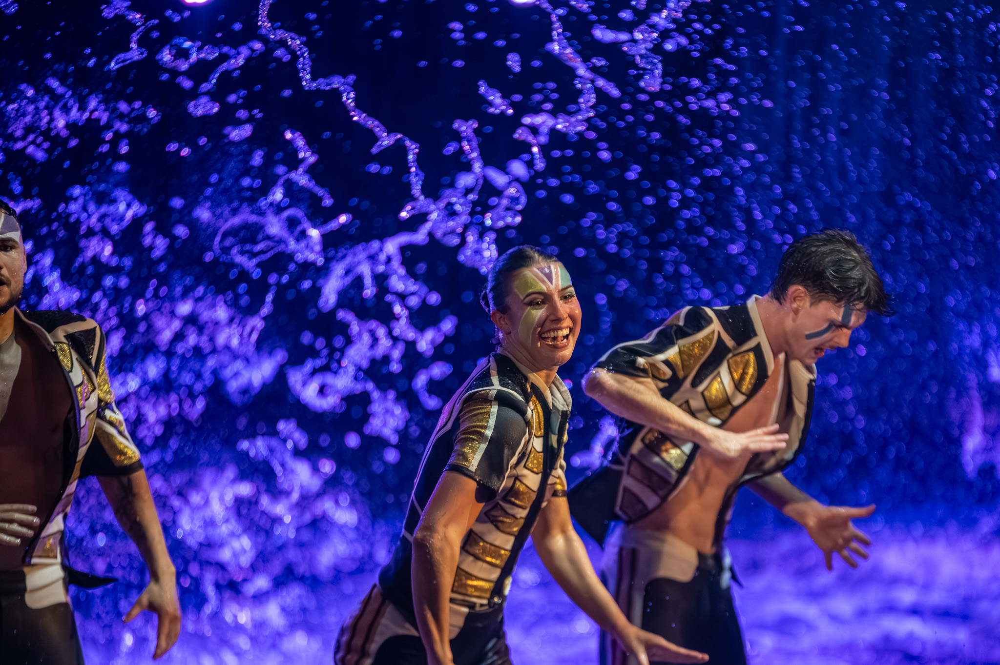 Performer and dancers caught in warm stage light over water